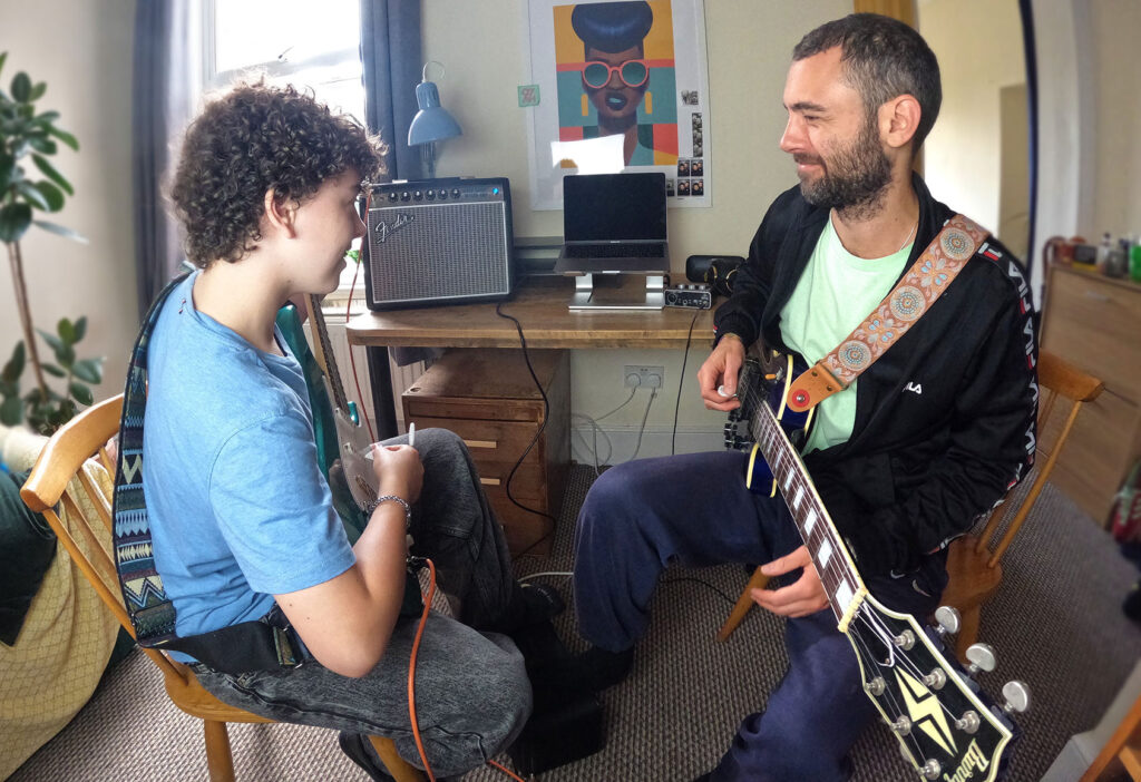 Student and guitar teacher doing a guitar lesson in a studio