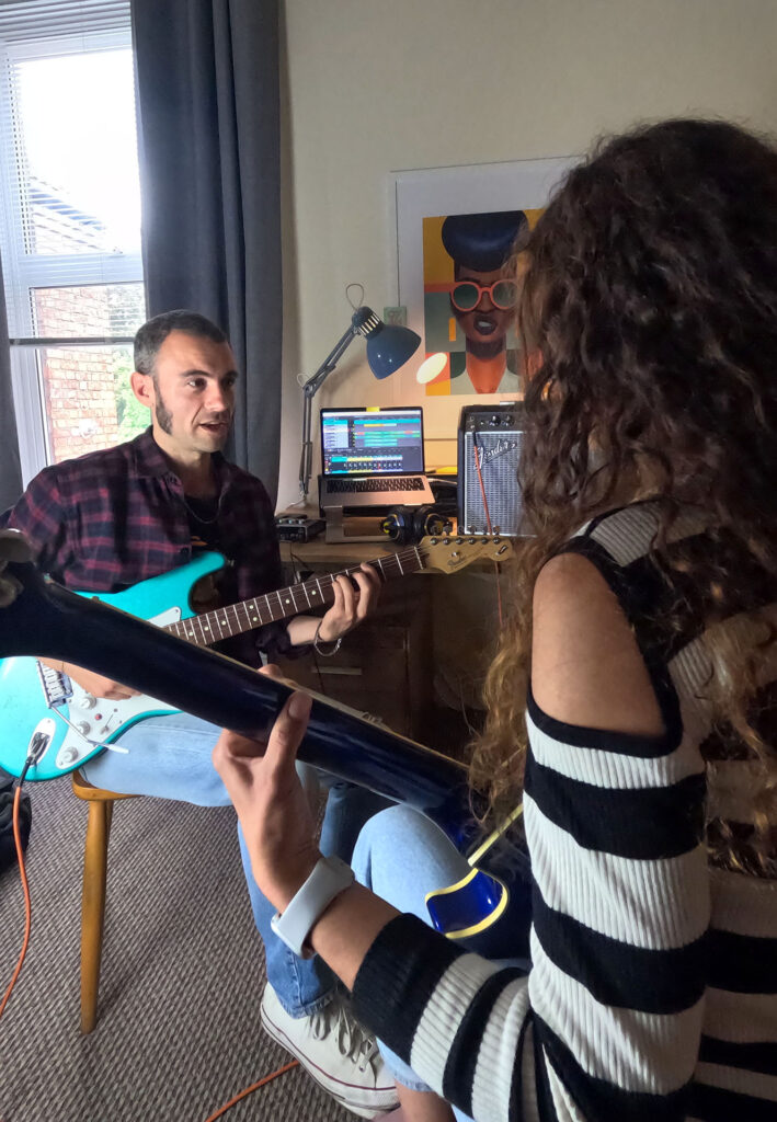 Guitar teacher in a studio session, giving advice to student