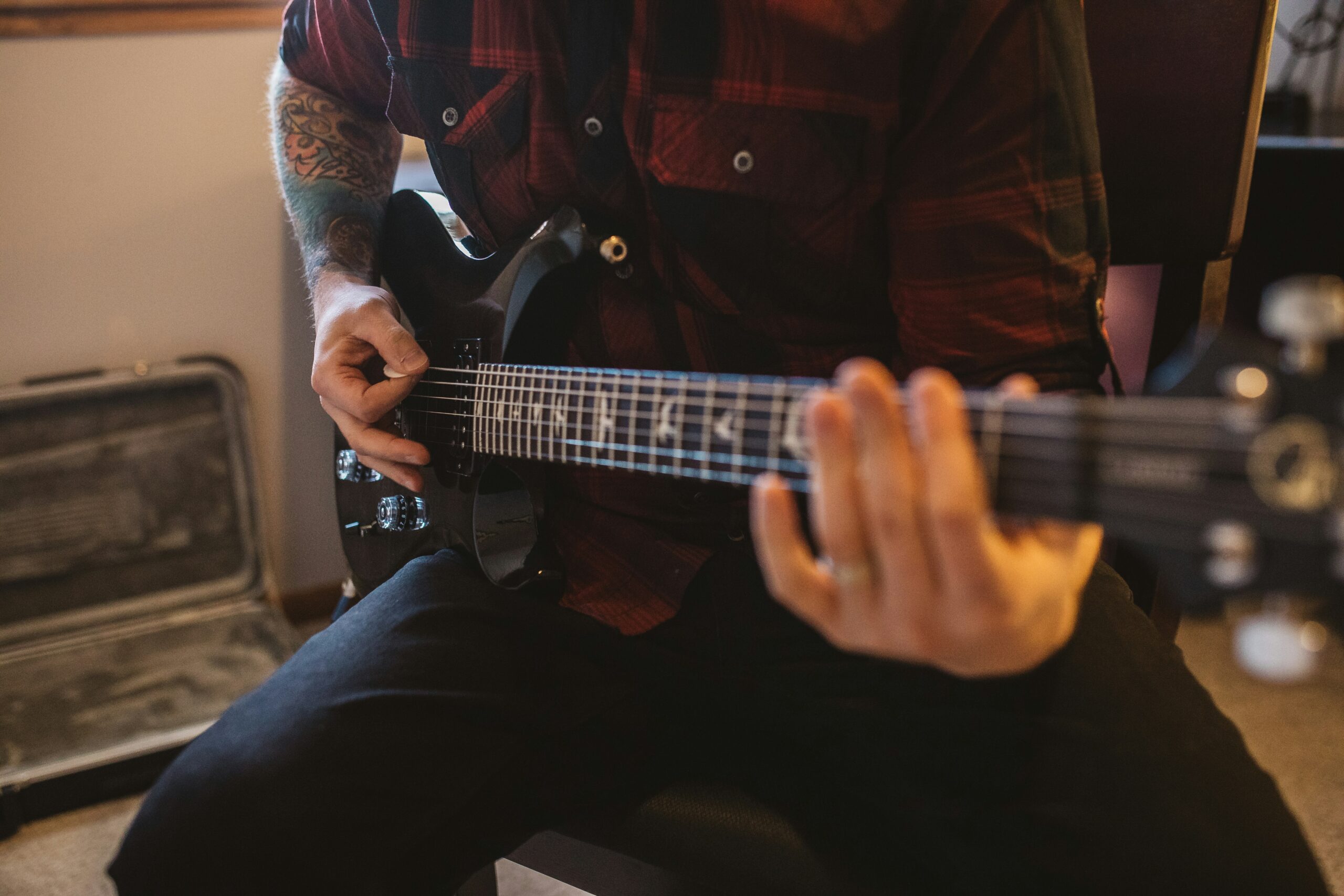 Close up photo of guitarist playing a black electric guitar